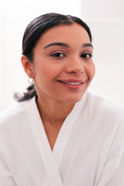 Young beautiful lady smiling while posing for a photo in a white bathrobe