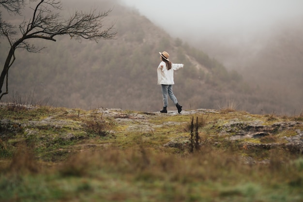 Young beautiful lady walks in spring hills in foggy time at dawn. Mystic, cold and nature.