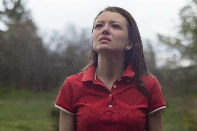 若い美しい女性、涙で濡れた女性、夏の雨の下で女性。動揺して泣いて、雨滴に顔をさらしている少女。