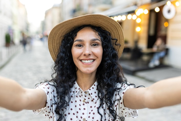 Young beautiful latin american woman walking in evening city woman looking into smartphone camera