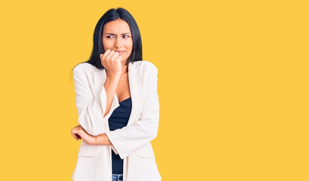 Young beautiful latin girl wearing business clothes looking stressed and nervous with hands on mouth biting nails anxiety problem