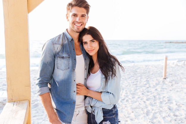 Young beautiful laughing couple looking at each other standing at the beach