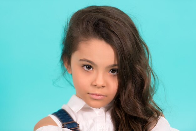 Young beautiful little girl with dark hair on blue background