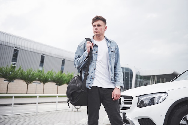 Un giovane uomo bello all'aeroporto sta aspettando il volo.