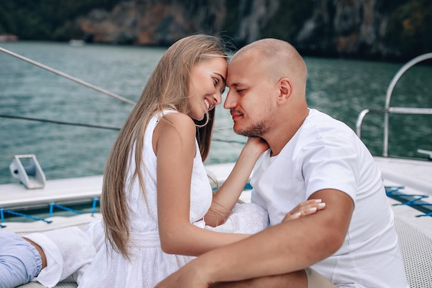 Young beautiful married couple kissing on the yacht on\
vacation. caucasian woman with long hair and bald man in the\
andaman sea. phuket.