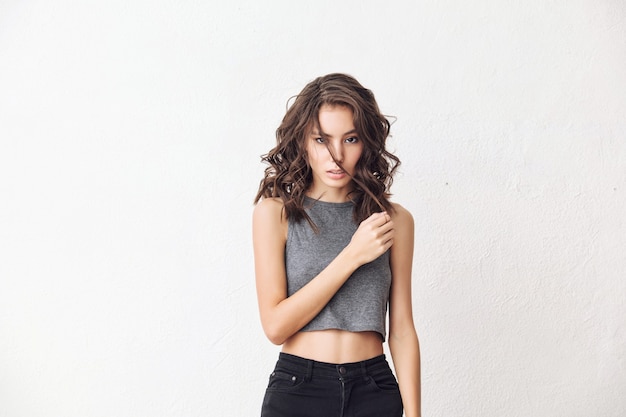 Young beautiful model with natural makeup and beautiful hair on a white background in a gray t-shirt