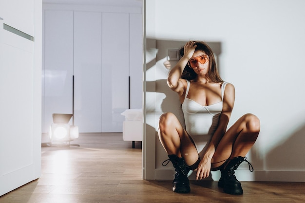 A young beautiful model woman is standing posing in the kitchen in white underwear the girl has long