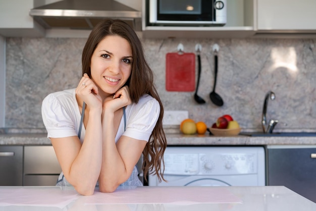 Young beautiful modern woman stands near table in kitchen at home Cute smiling