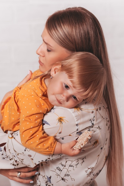 Young beautiful mom gently hugs her little daughter. Vertical