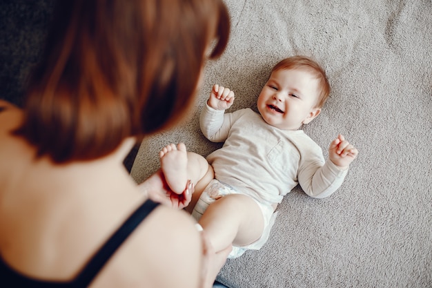 A young and beautiful mom playing with his little son at home