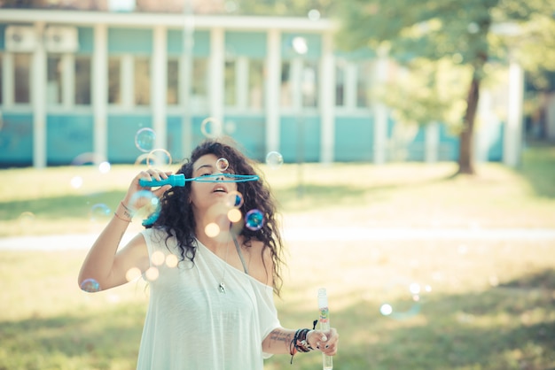 young beautiful moroccan curly woman blowing bubbles