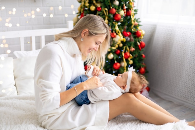 Young beautiful mother and baby celebrating Christmas at home with a Christmas tree anddecorations