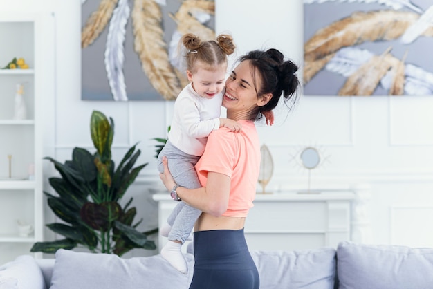 Young beautiful mother having fun with her toddler daughter at cozy home