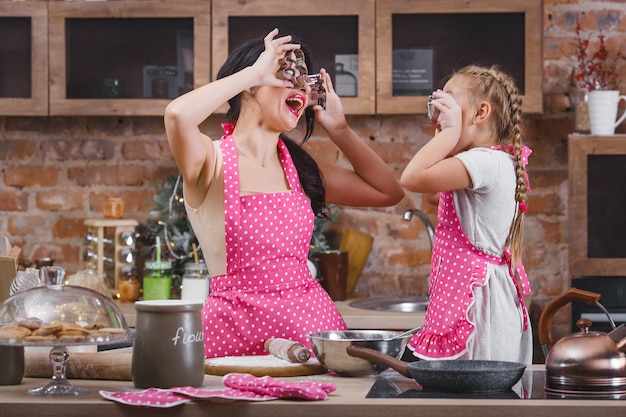 Young beautiful mother and her little daughter cooking together at the kitchen