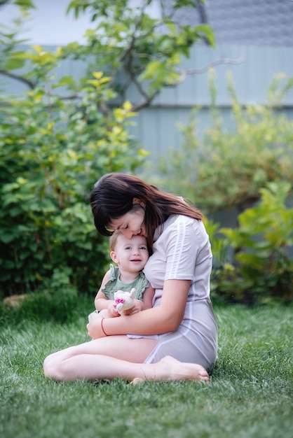 Young beautiful mother holds the baby in her arms in a green park