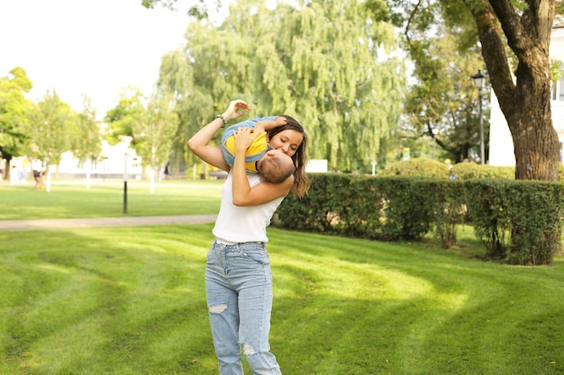 a young beautiful mother hugsher little son in a yellow Tshirt and jeans in the park