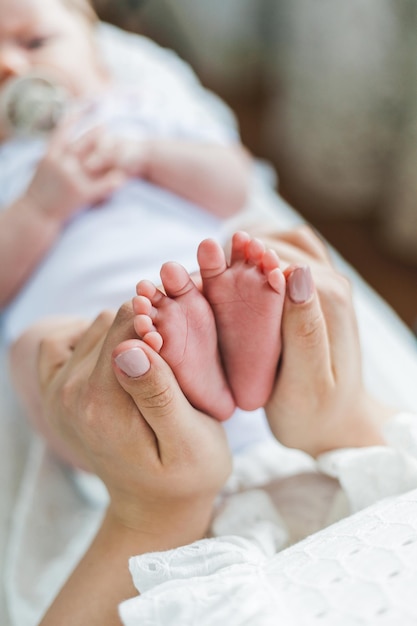 Young beautiful mother with blue eyes holds her little newborn daughter in her arms