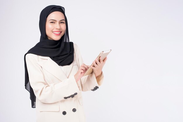 Молодая красивая мусульманская деловая женщина в костюме с планшетом на белом фоне студии