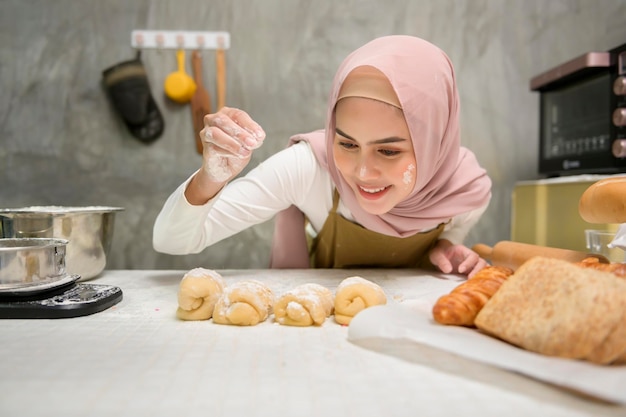 Young beautiful muslim woman is baking in her kitchen bakery and coffee shop business