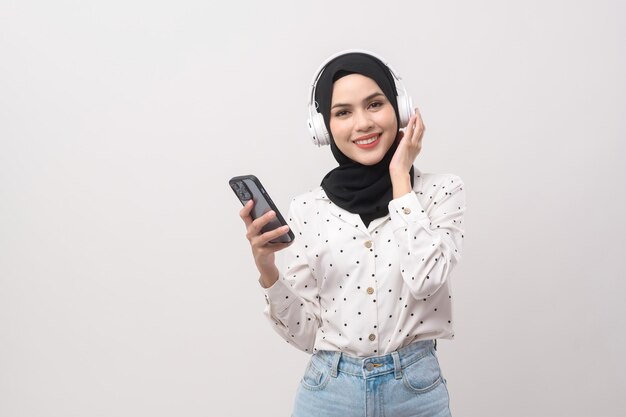 Young beautiful muslim woman wearing headset on white background