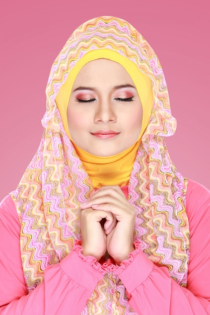 Hijab를 입고 분홍색 의상을 가진 젊은 아름 다운 이슬람 여성