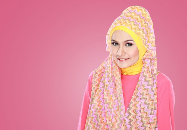 Hijab를 입고 분홍색 의상을 가진 젊은 아름 다운 이슬람 여성