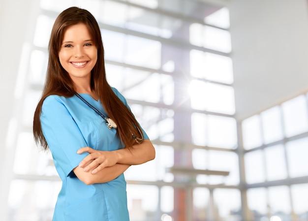 Young beautiful nurse on blurred hospital background