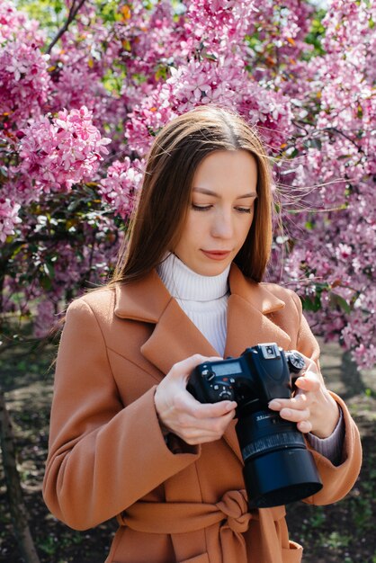 Young beautiful photographer walks and takes photos in a garden