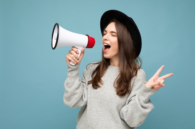 young beautiful positive brunette woman with sincere emotions wearing stylish black hat and