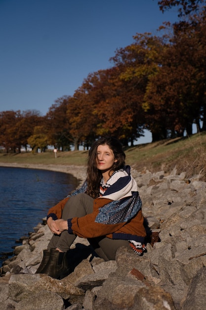 Young beautiful positive girl with long hair near the river on a sunny day.