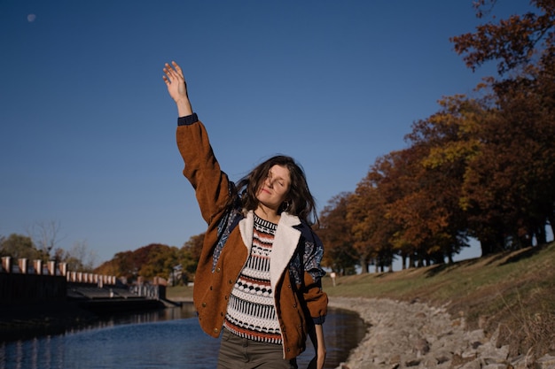 Young beautiful positive girl with long hair near the river on a sunny day.