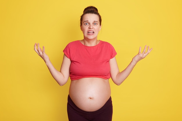 Young beautiful pregnant female with shocked facial expression