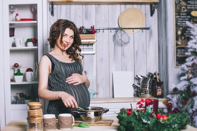 Young beautiful pregnant with at home in the kitchen smiling happy