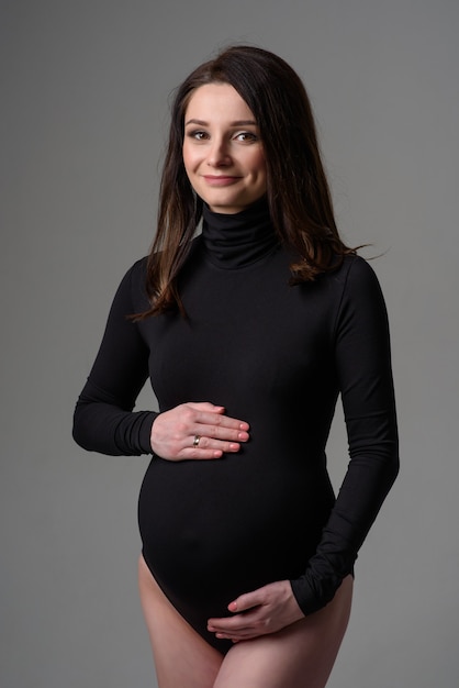 Young beautiful pregnant woman in black bodysuit.