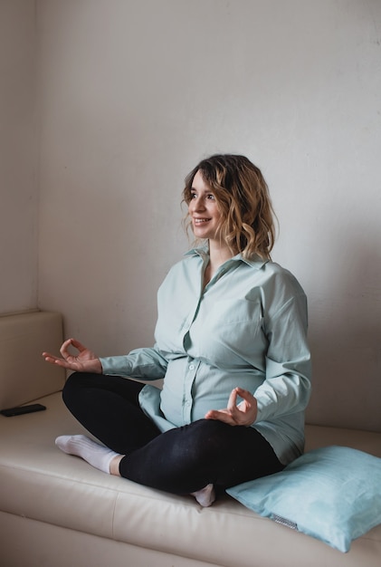 Young beautiful pregnant woman is doing yoga at home. Poses relaxation, calm down, relax.