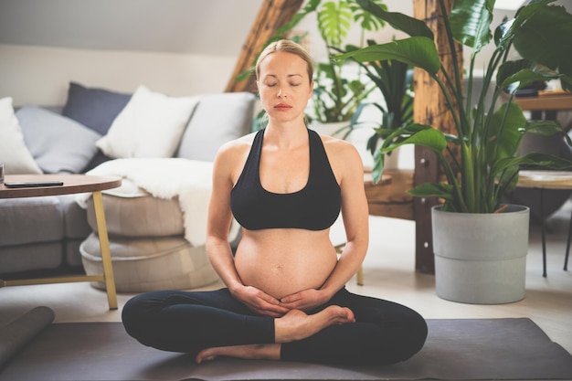 Giovane bella donna incinta formazione yoga accarezzando il suo ventre giovane felice in attesa rilassante pensando al suo bambino e godersi la sua vita futura concetto di yoga gravidanza maternità