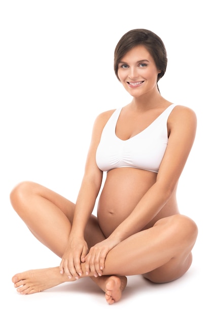 Young and beautiful pregnant woman on white wall