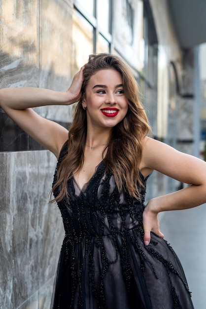 Young beautiful pretty girl posing in dress along in urban background