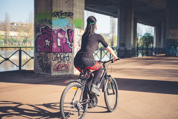 Foto bici di guida della giovane ragazza bella punk scura