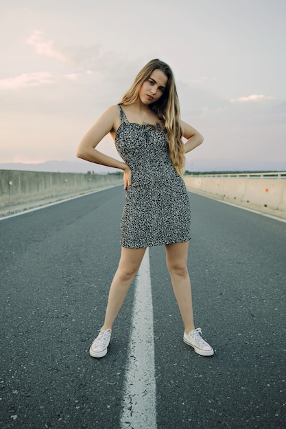 Young beautiful rebel woman on empty road at sunset