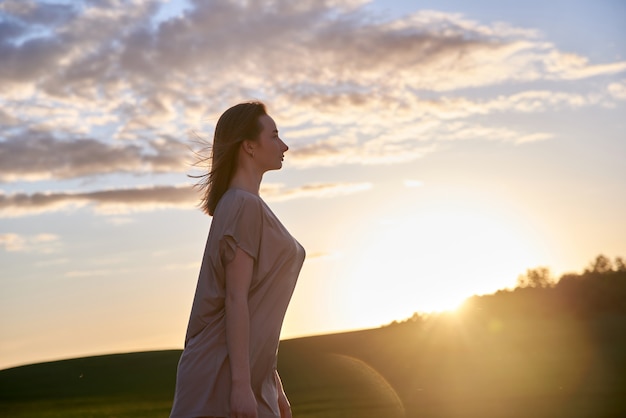 麦畑で若くて美しい赤髪の女性は夕日を見てください。