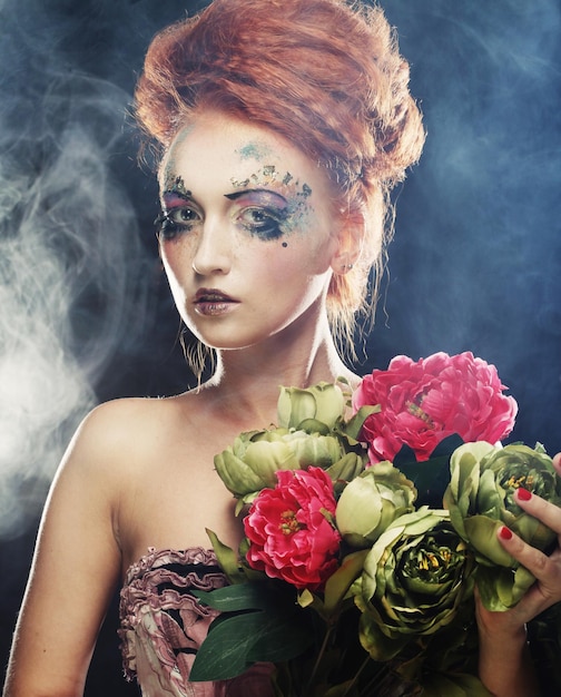 Young beautiful redhair woman with bright creative visage holding flowers