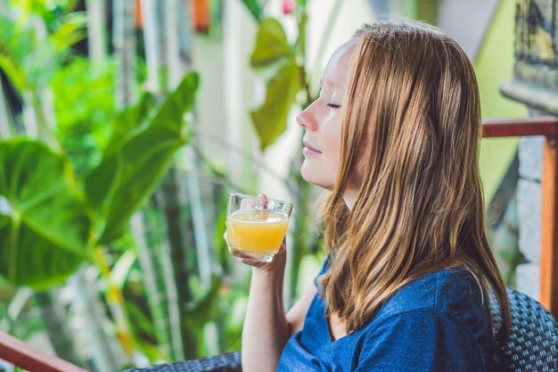 カフェでおいしい朝の生姜茶を飲むカフェに座っている若い美しい赤毛の女性