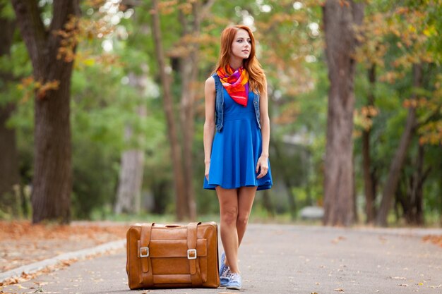 Young beautiful redhead woman with suitcase at outdoor