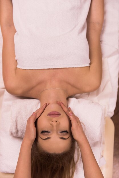 Young beautiful relaxed woman receiving a head massage in a spa centre