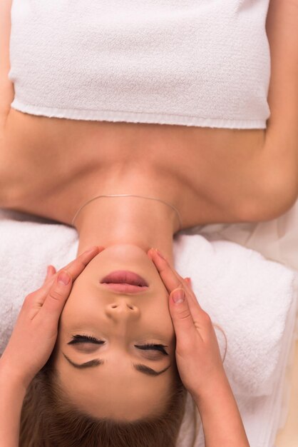 Young beautiful relaxed woman receiving a head massage in a spa centre