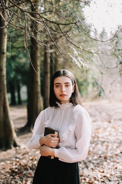 young beautiful school or college girl reading a book in the park