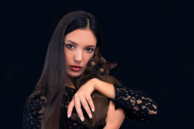 Giovane bella donna sexy con trucco luminoso con un gatto in mano