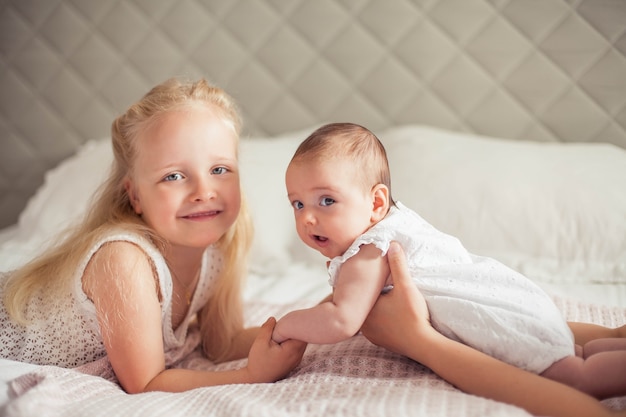 Young beautiful sister holds a baby