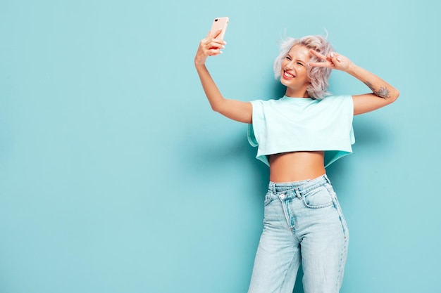 Young beautiful smiling female in trendy summer clothes Sexy carefree woman posing near in studio Positive blond model having fun and going crazy Cheerful and happy